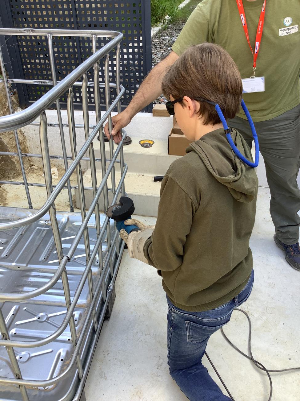 A student and an AU volunteer work on the metal frame of an aquaponics system.