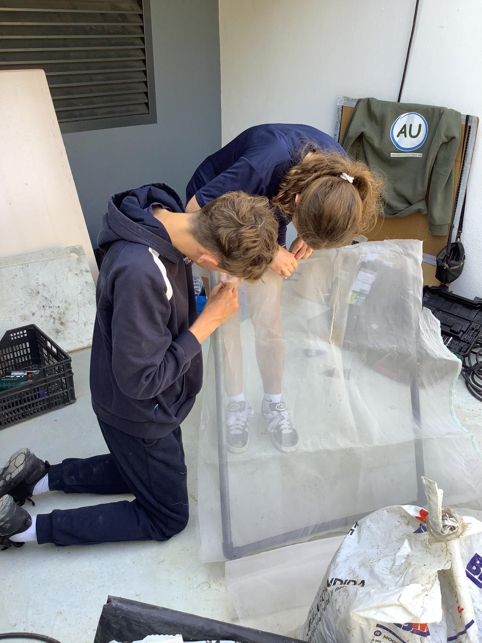 Two students work together to build a protective panel for fish.